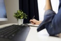 Woman`s hands with pen writing on notebook. Modern grey office d