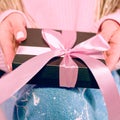 Woman`s hands with pink manicure holding black present box Royalty Free Stock Photo