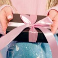 Woman`s hands with pink manicure holding black present box Royalty Free Stock Photo