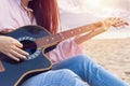 Woman`s hands playing acoustic guitar, capture chords by finger on sandy beach at sunset time. playing music concept Royalty Free Stock Photo