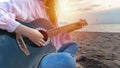 Woman`s hands playing acoustic guitar, capture chords by finger on sandy beach at sunset time. playing music concept Royalty Free Stock Photo