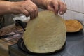 The woman`s hands pour the pancake batter into a hot pan and fry them on both sides, turning them over with her hands.