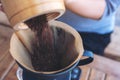 Woman`s hands pouring coffee grounds from wooden grinder into a drip coffee filter Royalty Free Stock Photo