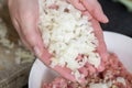 Woman& x27;s hands pouring small onion cubes into meat close-up. The process of cooking meat.