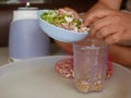 A woman`s hands preparing / putting food ingredients in a small blender cup for blending for cooking food at home