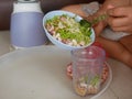 A woman`s hands preparing / putting food ingredients in a small blender cup for blending for cooking food at home