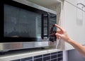 Woman`s Hands pressing button on black microwave Royalty Free Stock Photo