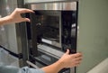 Woman`s Hands pressing button to open microwave door