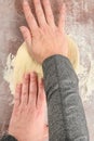 Womanâs hands pressing and spreading raw pizza dough on a clear plastic mat, preparation for baking