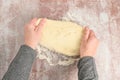 Womanâs hands pressing and spreading raw pizza dough on a clear plastic mat, preparation for baking