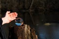 Woman`s hands protecting Clear Quartz Sphere on bark, rhytidome, reflecting lake, forest and sky