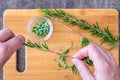 WomanÃ¢â¬â¢s hands pulling fresh rosemary leaves off a sprig, sprigs of rosemary with on a bamboo cutting board, chopped rosemary, pa Royalty Free Stock Photo