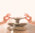 Woman`s hands put a feather on a pyramid of stones. Equilibrium, Balance concept. Zen stones on white