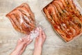 Woman`s hands putting big prawns, shrimps in plastic freezer bag, seafood on wooden background