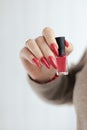 Woman`s hands with long nails and a bottle of red orange nail polish Royalty Free Stock Photo