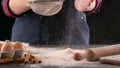 Woman`s hands sifts flour through a sieve into the kitchen table.