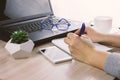 Hands with smartphone on a bsckground of working place with laptop,succulent and coffee cup Royalty Free Stock Photo