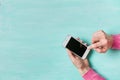 Woman`s hands with smartphone on turquoise background. Girl holding phone and typing. Communication concept