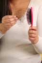 Woman\'s hands take a hairbrush with many fallen hairs after brushing for alopesia, anemia or postpartum disease