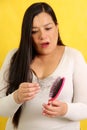 Woman's hands take a hairbrush with many fallen hairs after brushing for alopesia, anemia or postpartum disease