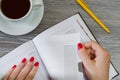 Woman`s hands taking a page out of her notepad. Cup of tea, pen Royalty Free Stock Photo