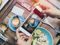 Woman`s hands taking photo of coffee cup on wooden table by smartphone Royalty Free Stock Photo