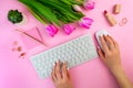 Woman`s hands typing on the keyboard. Feminine work space on pink flat lay. Remote distant home office, freelance, distance