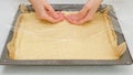 Woman`s hands using plastic wrap unfurl pizza dough onto prepared baking pan. Homemade pizza