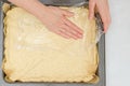 Woman`s hands using plastic wrap unfurl pizza dough onto prepared baking pan.