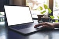 A woman`s hands using and touching laptop touchpad with blank white desktop screen with coffee cup on wooden table in cafe Royalty Free Stock Photo