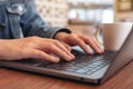 A woman`s hands using and typing on laptop computer keyboard with coffee cup on the table Royalty Free Stock Photo