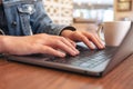 Woman`s hands using and typing on laptop computer keyboard with coffee cup on the table Royalty Free Stock Photo