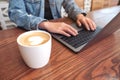 Woman`s hands using and typing on laptop computer keyboard with coffee cup on the table Royalty Free Stock Photo