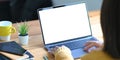 A woman`s hands using a white blank screen computer laptop at the wooden working desk Royalty Free Stock Photo