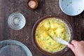 WomanÃ¢â¬â¢s hands whisking raw egg mixture with chopped broccoli in glass bowl, on a wood table