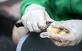 Woman`s hands in white gloves peel raw new potatoes, close-up. Cleaning organic potatoes. Detail of female hands peeling fresh Royalty Free Stock Photo