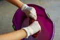 Woman`s hands in white gloves wringing towel into bucket.