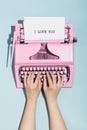 Woman`s hands writing `I love you` on an oldschool pink typewriter. Royalty Free Stock Photo