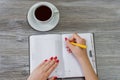 Woman`s hands writing information in a notepad. Cup of tea is on Royalty Free Stock Photo