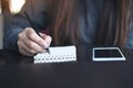 A woman`s hands writing on notebook with mobile phone on the table Royalty Free Stock Photo