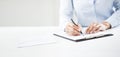 Woman`s hands writing on sheet in a clipboard with a pen Royalty Free Stock Photo