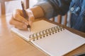 woman`s hands writing in spiral notepad placed