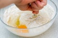 Woman`s hands with an yeast dough. The woman has added the yolk of a chicken egg and is stirring the baking dough in a glass bowl Royalty Free Stock Photo