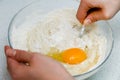 Woman`s hands with an yeast dough. The woman has added the yolk of a chicken egg and is stirring the baking dough in a glass bowl Royalty Free Stock Photo