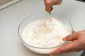 Woman`s hands with an yeast dough. The woman is stirring the baking dough in a glass bowl Royalty Free Stock Photo