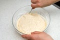 Woman`s hands with an yeast dough. The woman is stirring the baking dough in a glass bowl Royalty Free Stock Photo