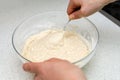 Woman`s hands with an yeast dough. The woman is stirring the baking dough in a glass bowl Royalty Free Stock Photo