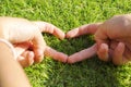 A woman`s heart-shaped hand touches the grass. artificial turf is not real grass. Royalty Free Stock Photo