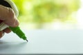 Woman holding green Liquid Correction Writing Pen or liquid paper for correct hand writing mistakes on white paper in bokeh