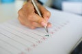 Woman`s holding pen on table lies a document with red and green check marks